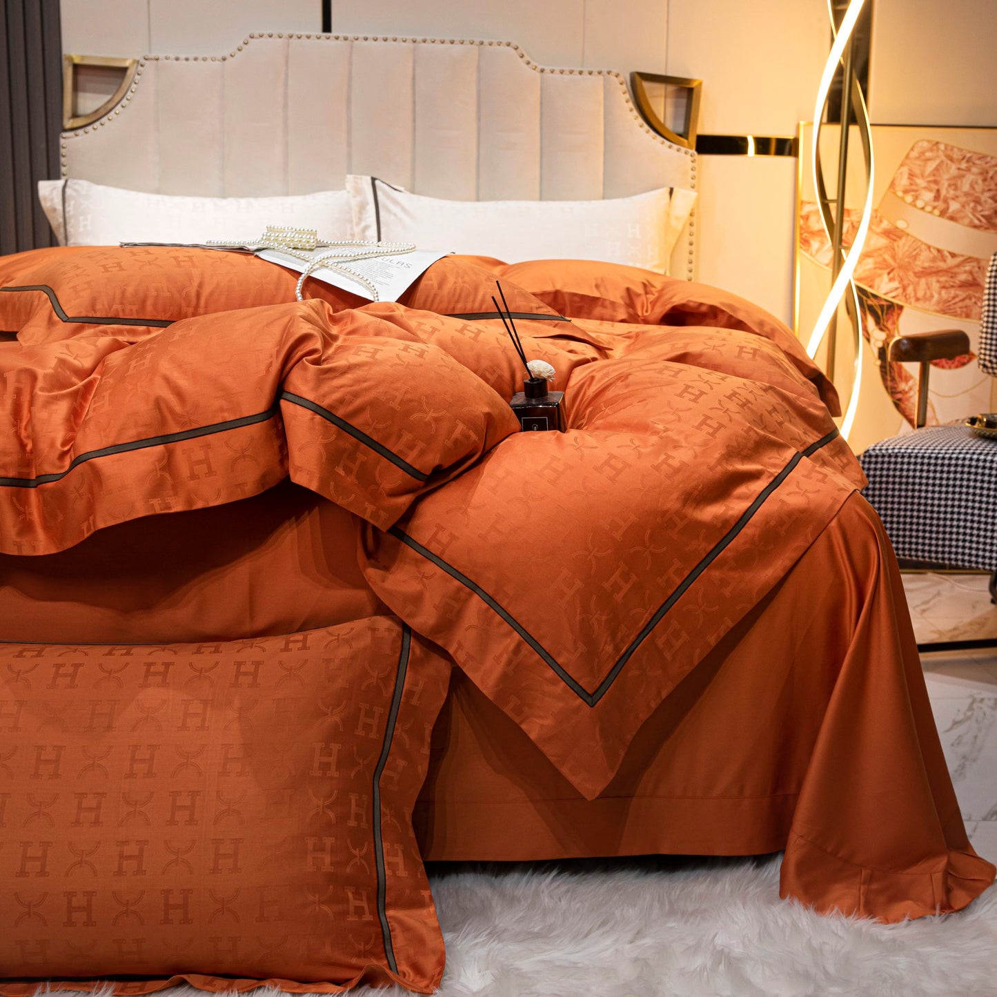 Luxurious tangerine sateen bedding set in Tencel cotton with black trim on a modern bed with white headboard.