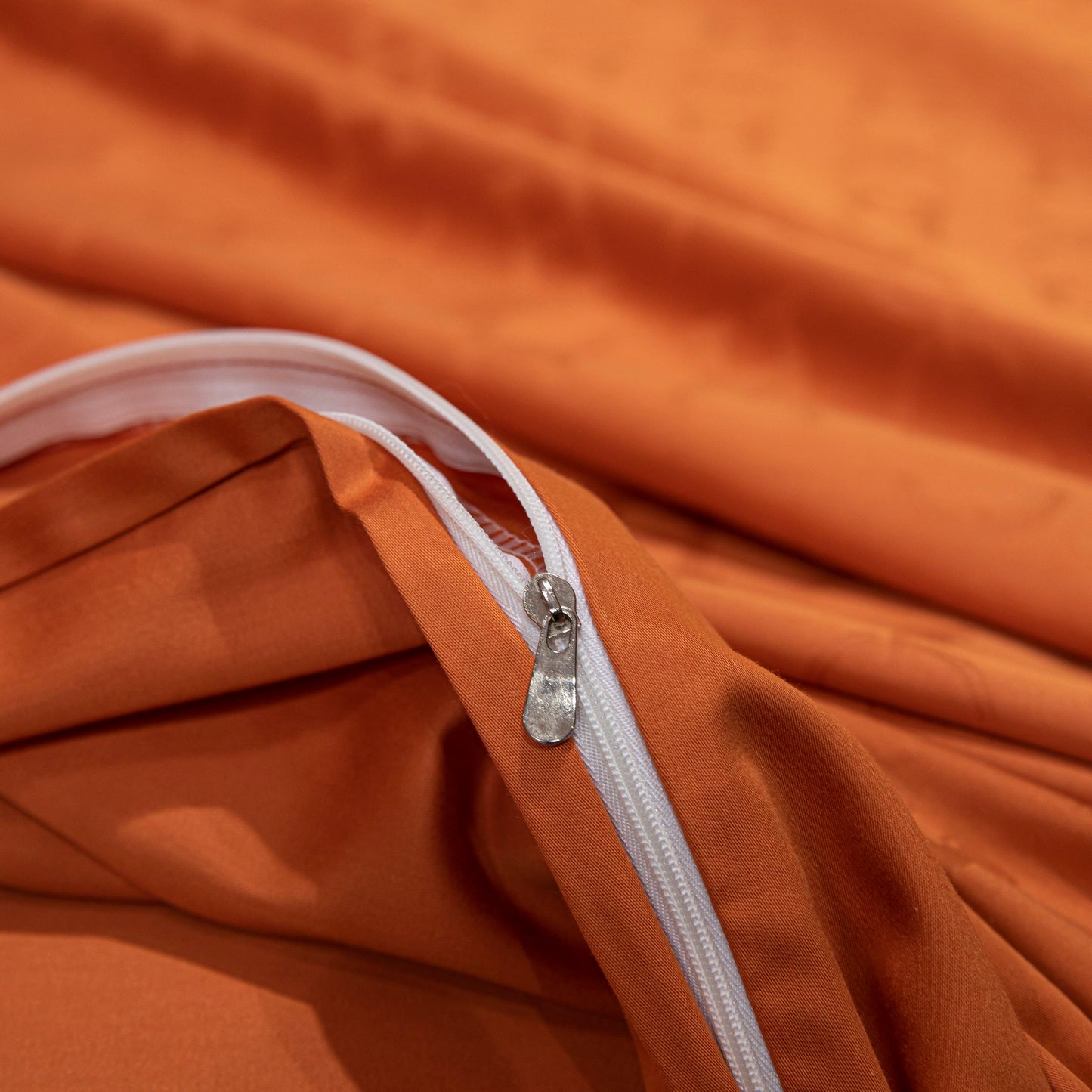 Close-up of a luxurious orange sateen bedding set zipper made from soft, breathable Tencel cotton fabric.