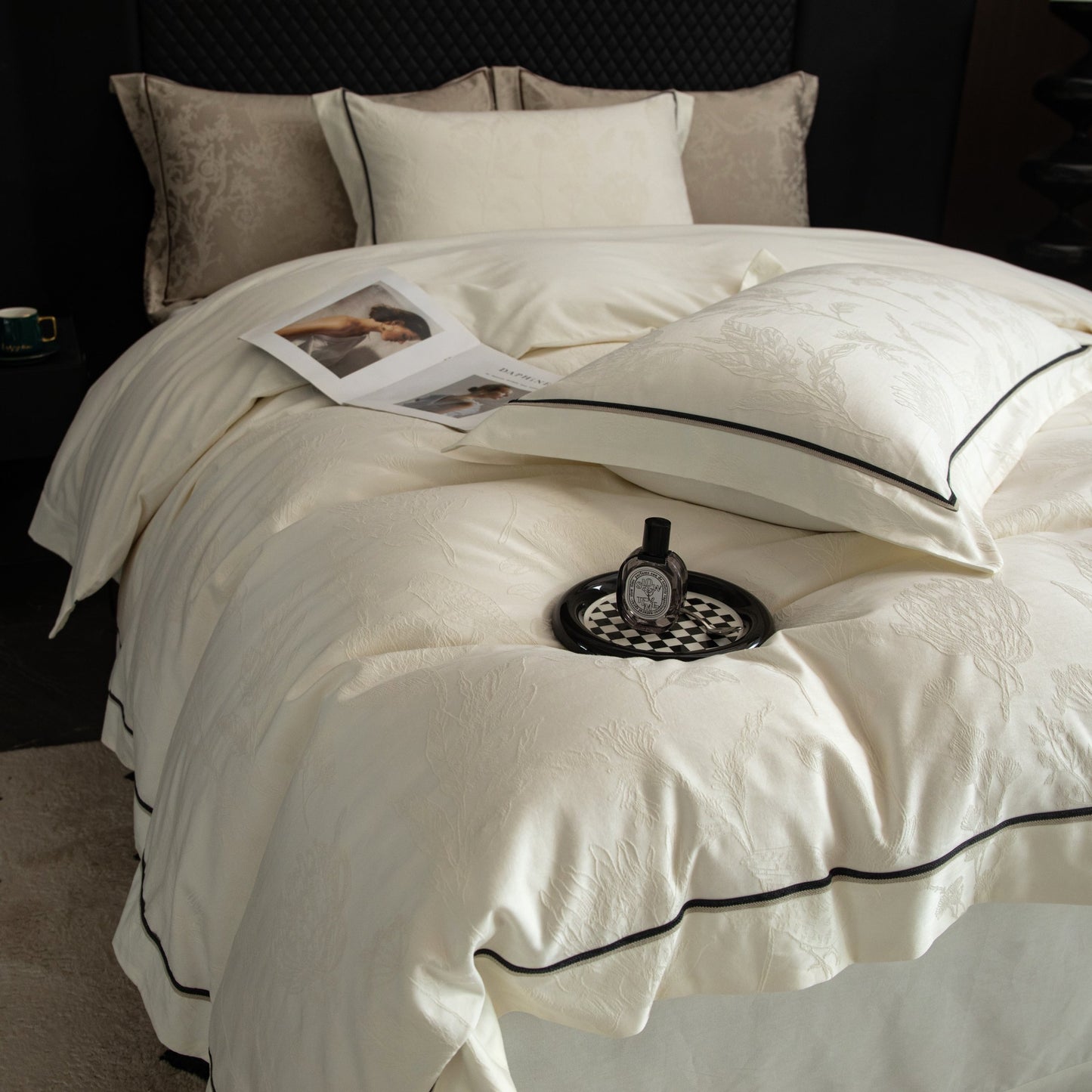 Luxurious cream sateen bedding set with subtle pattern and black trim on a neatly made bed in a cozy bedroom setting