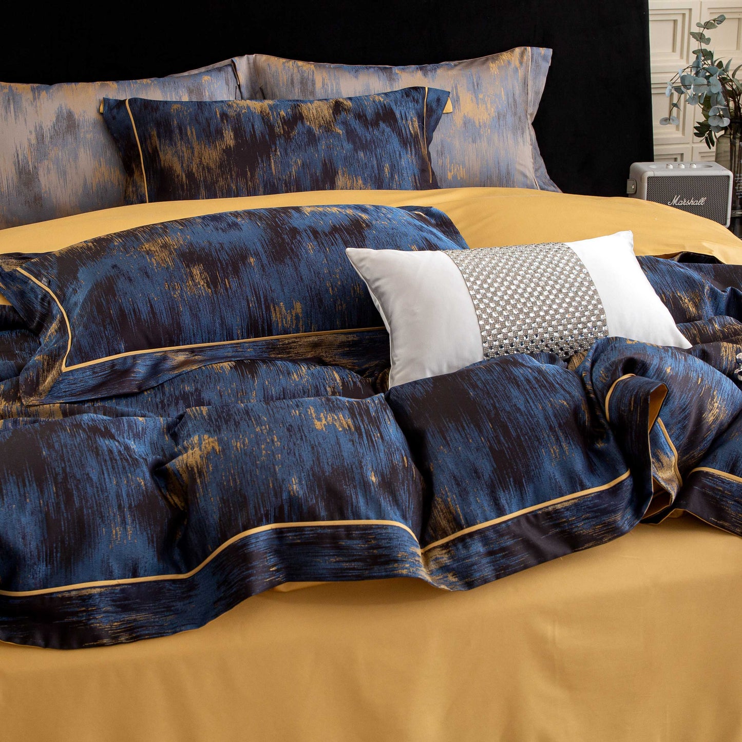 Luxurious Marrakech sateen bedding set in blue and gold tones with silky smooth Tencel cotton texture on bed.
