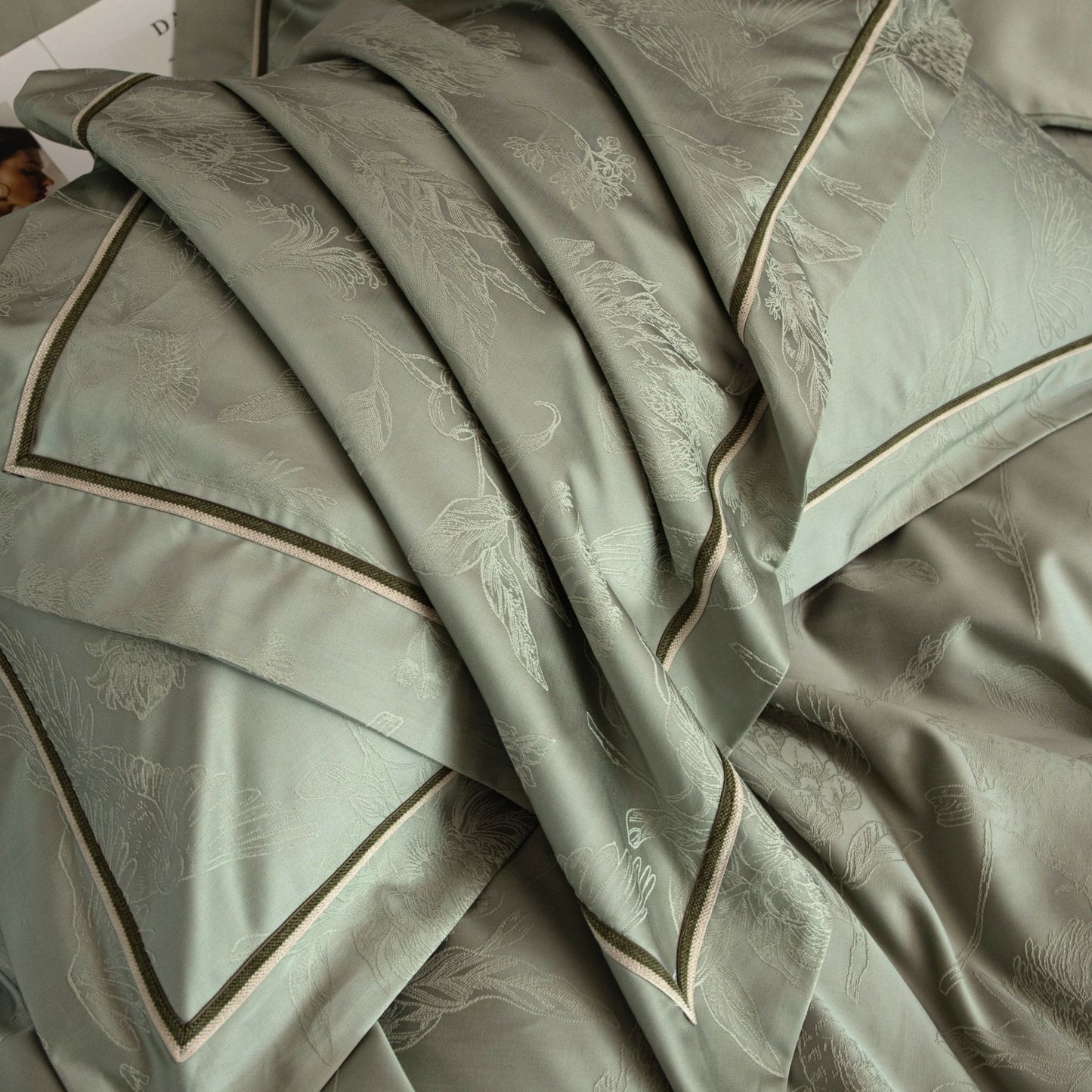 Luxurious Avignon sateen bedding set in soft green with subtle floral jacquard and contrasting trim detail.
