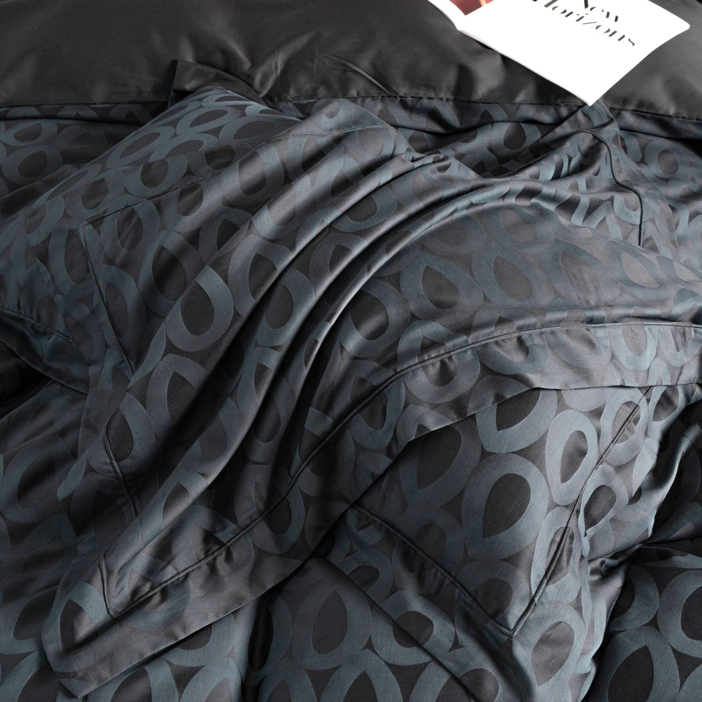 Close-up of Brooklyn sateen bedding set in deep charcoal with bold geometric pattern and silky smooth texture.