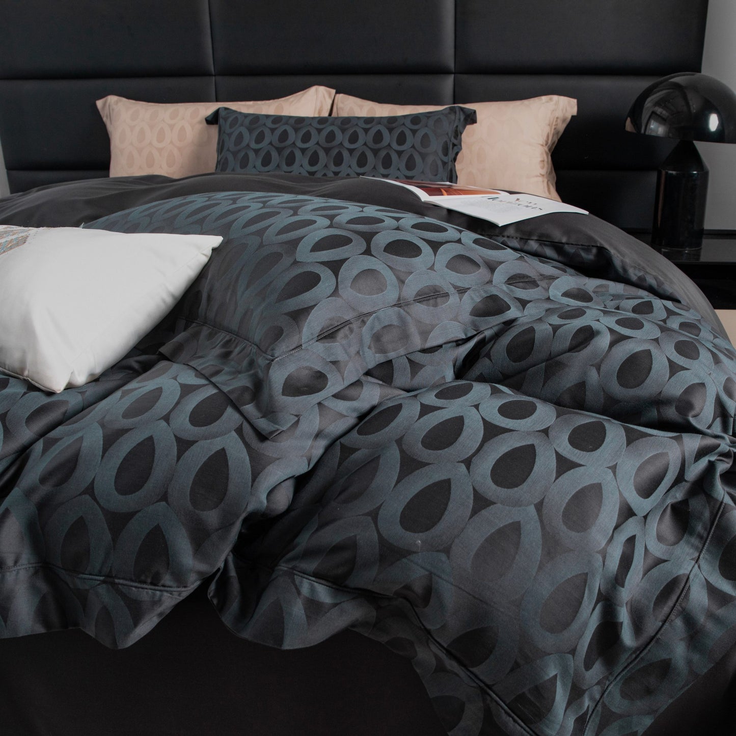 Modern geometric sateen bedding set in charcoal and slate grey with soft beige accent pillows on a black bed frame.