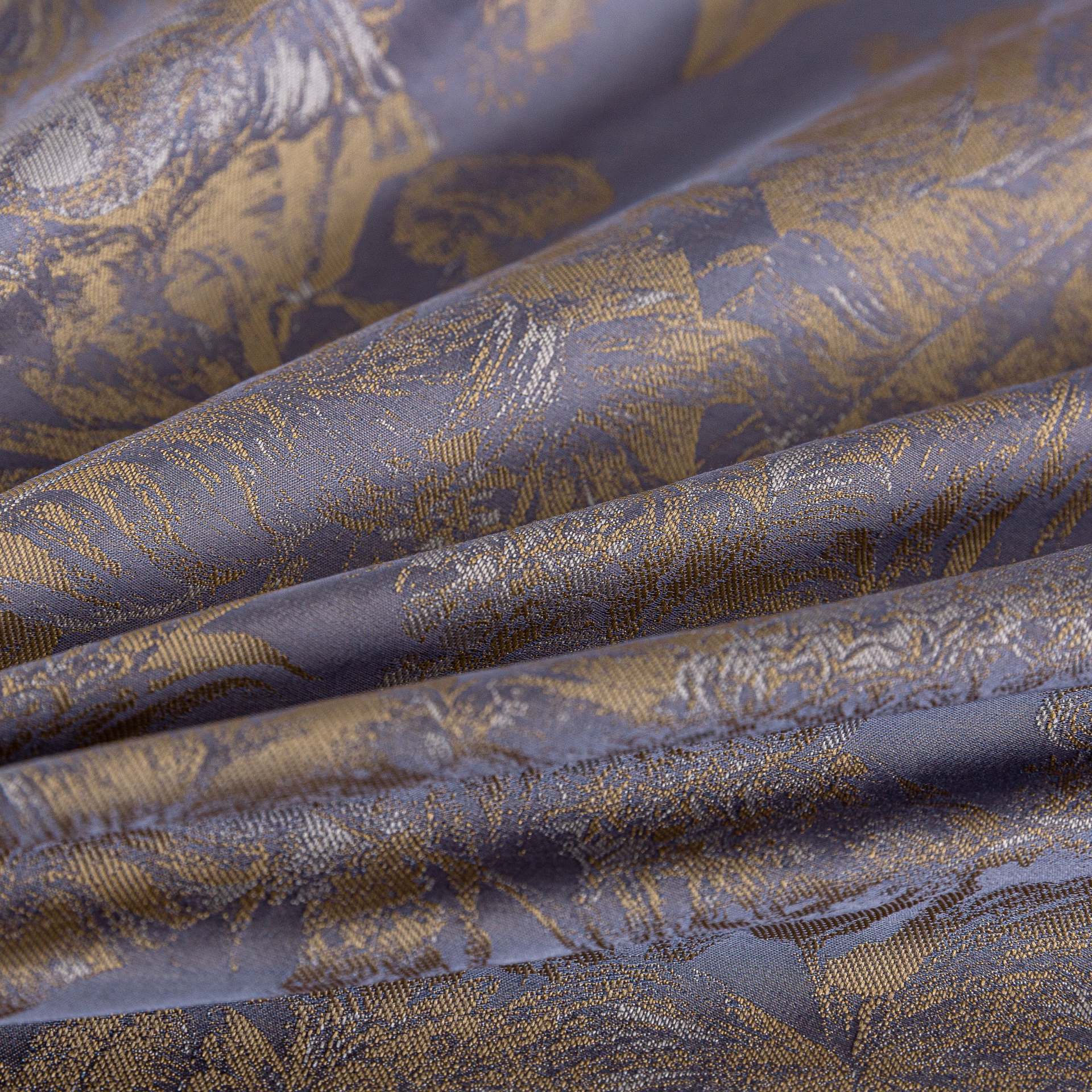 Close-up of luxurious purple and gold sateen bedding fabric with intricate floral pattern and smooth texture