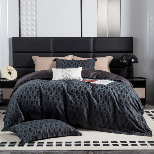 Modern geometric charcoal and slate grey sateen bedding set with neutral accent pillows on black upholstered bed.